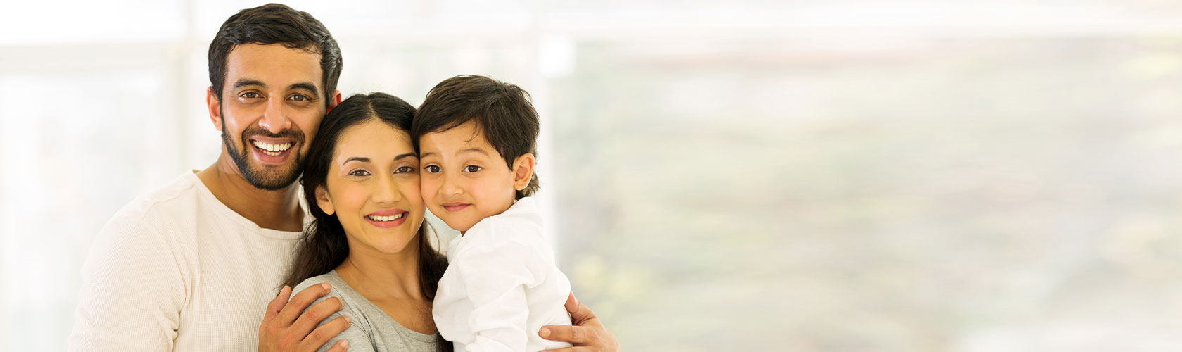 portrait of happy indian family of three standing indoors